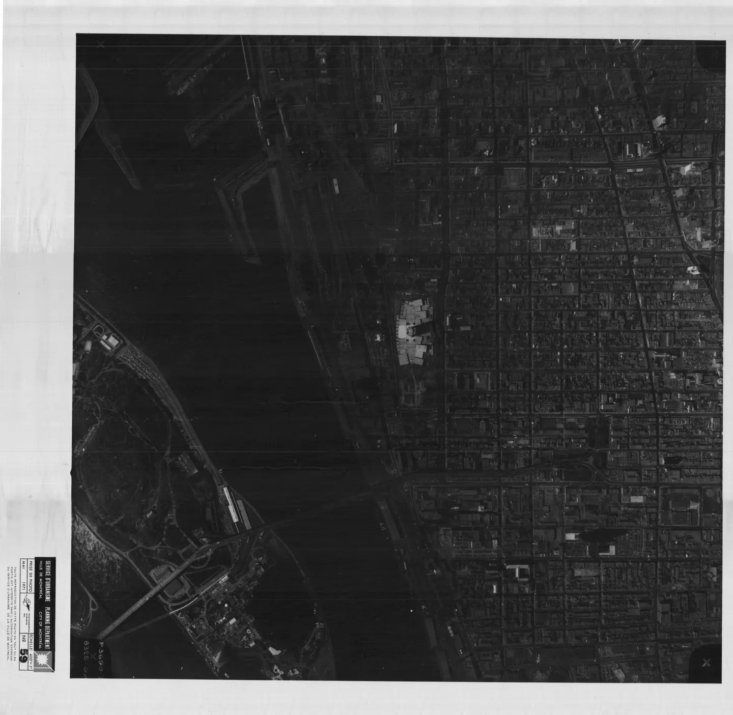 Photo noir et blanc d'un grand bâtiment près d'un plan d'eau, avec un pont et un parc