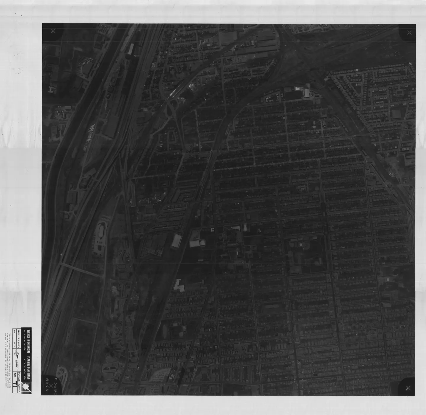 Photo en noir et blanc d'une rue avec un grand bâtiment en arrière-plan et des voitures garées