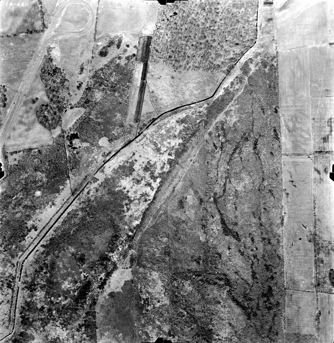 Photo en noir et blanc d'une route de terre et d'une voiture garée sur le côté