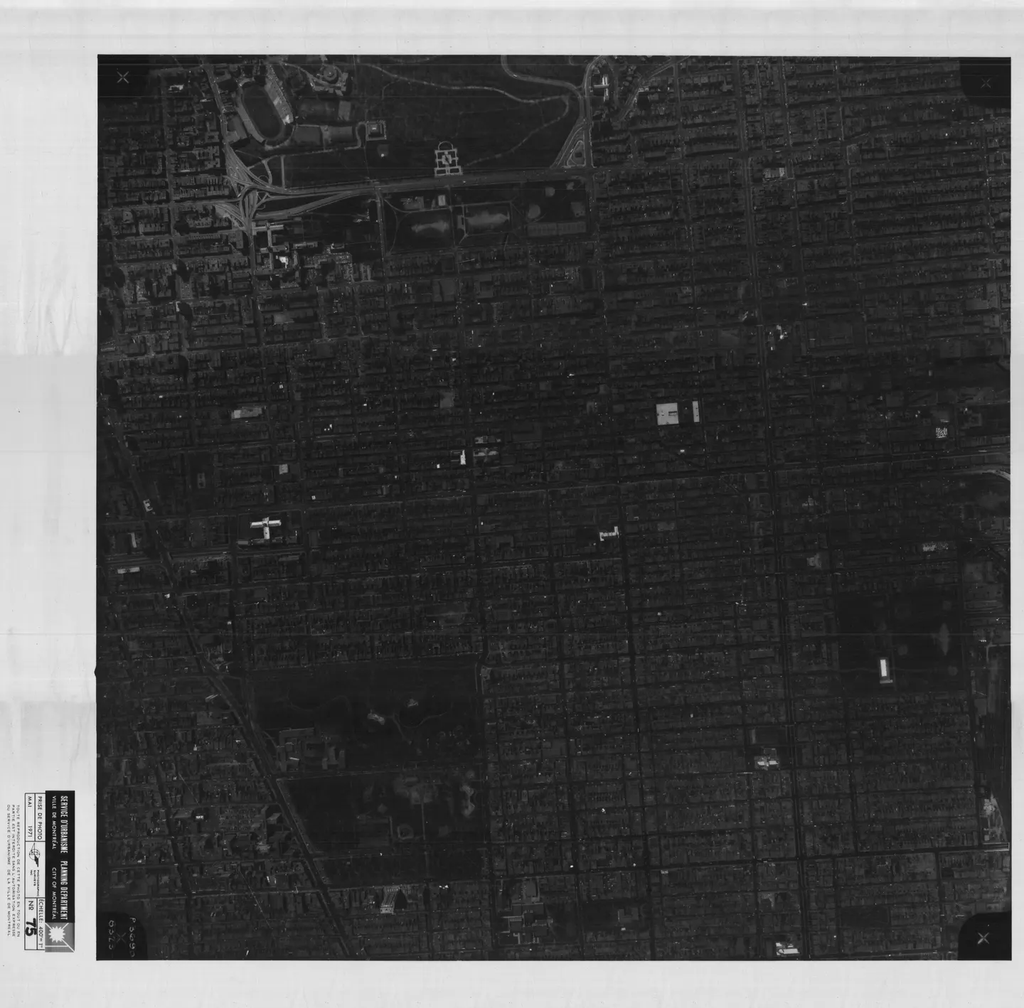 Photo en noir et blanc d'une rue animée avec bâtiments, voitures, un parc et une rivière