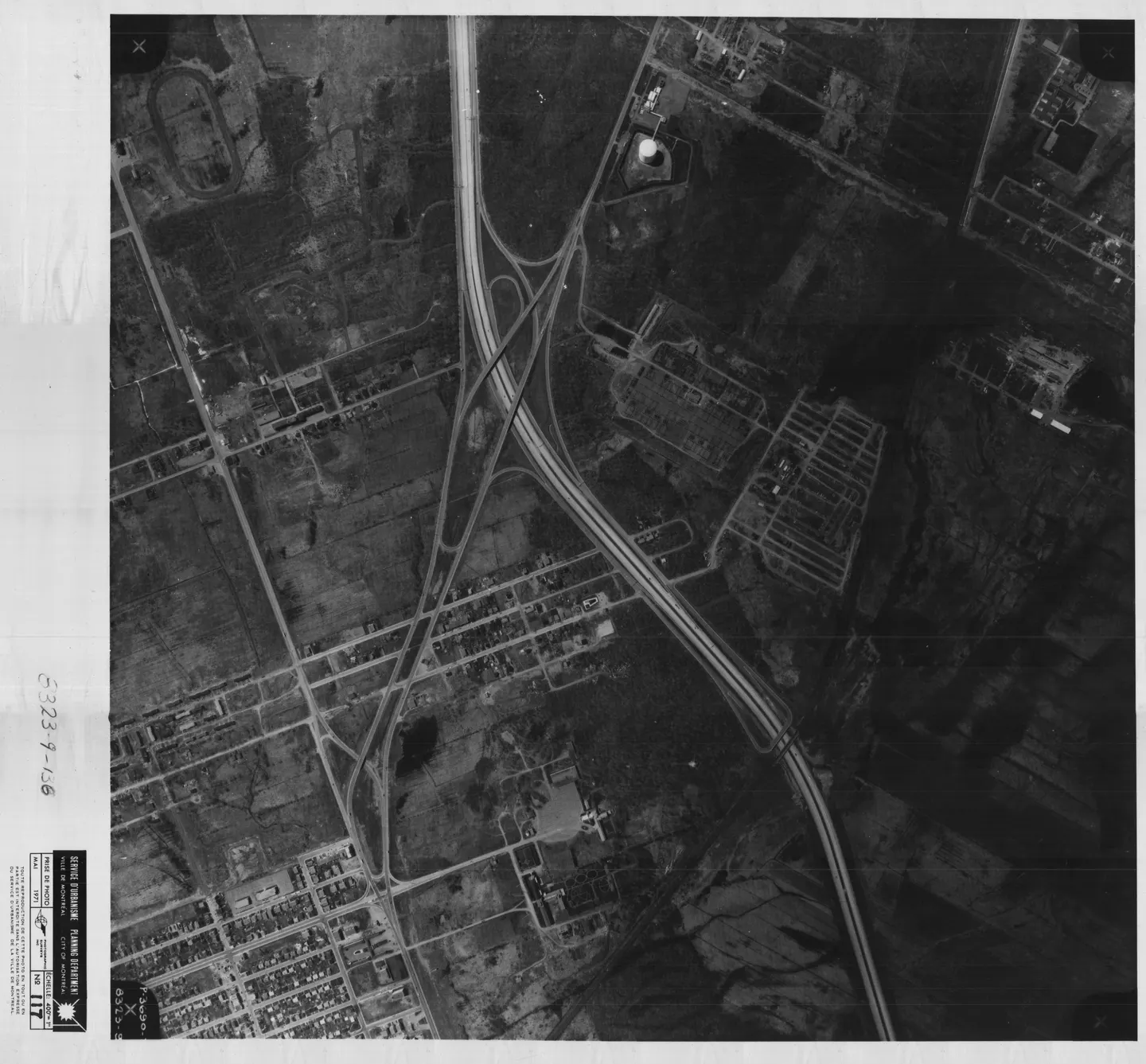 Rue en noir et blanc entourée de bâtiments, avec une autoroute à proximité