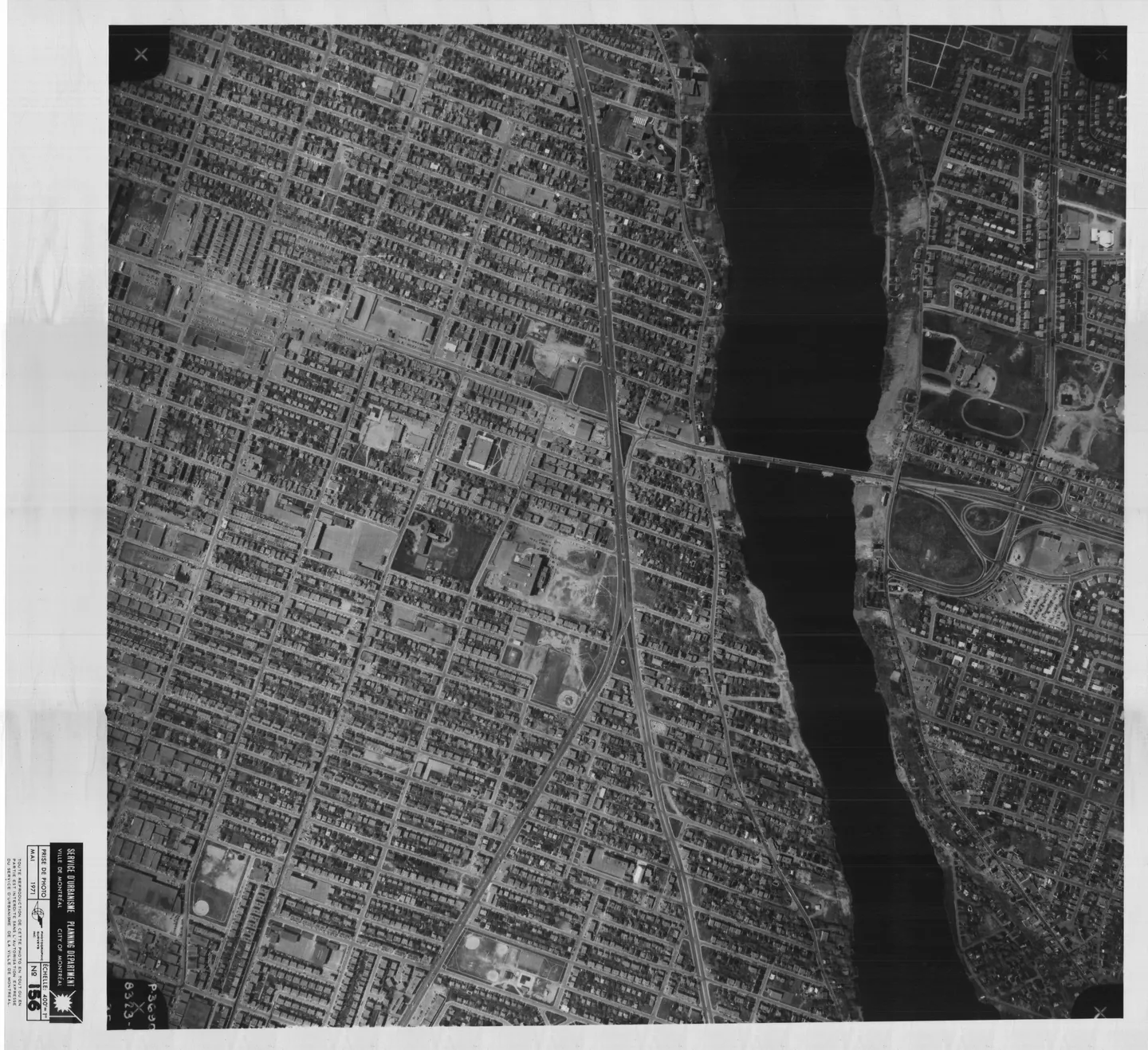 Photographie en noir et blanc d'une rue bordée de bâtiments et d'un parc à Montréal‑Nord