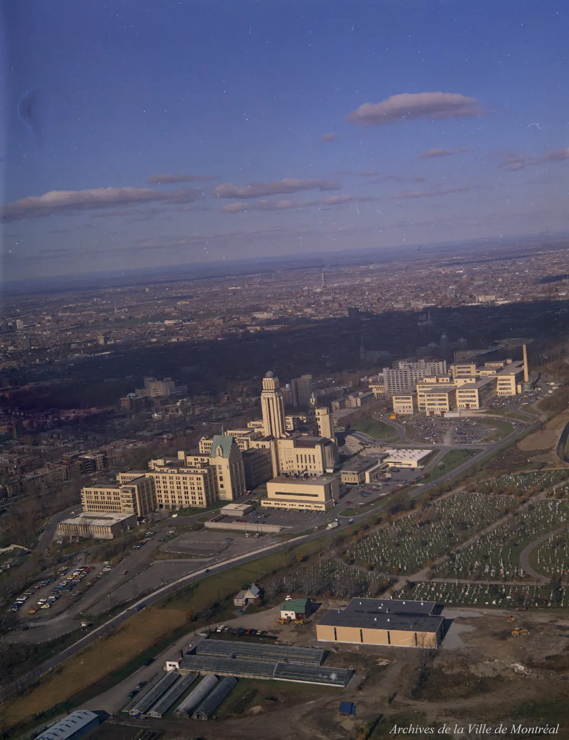 Vue oblique d'un bâtiment avec une tour d'horloge, entouré de voitures et de camions dans un paysage urbain de Montréal