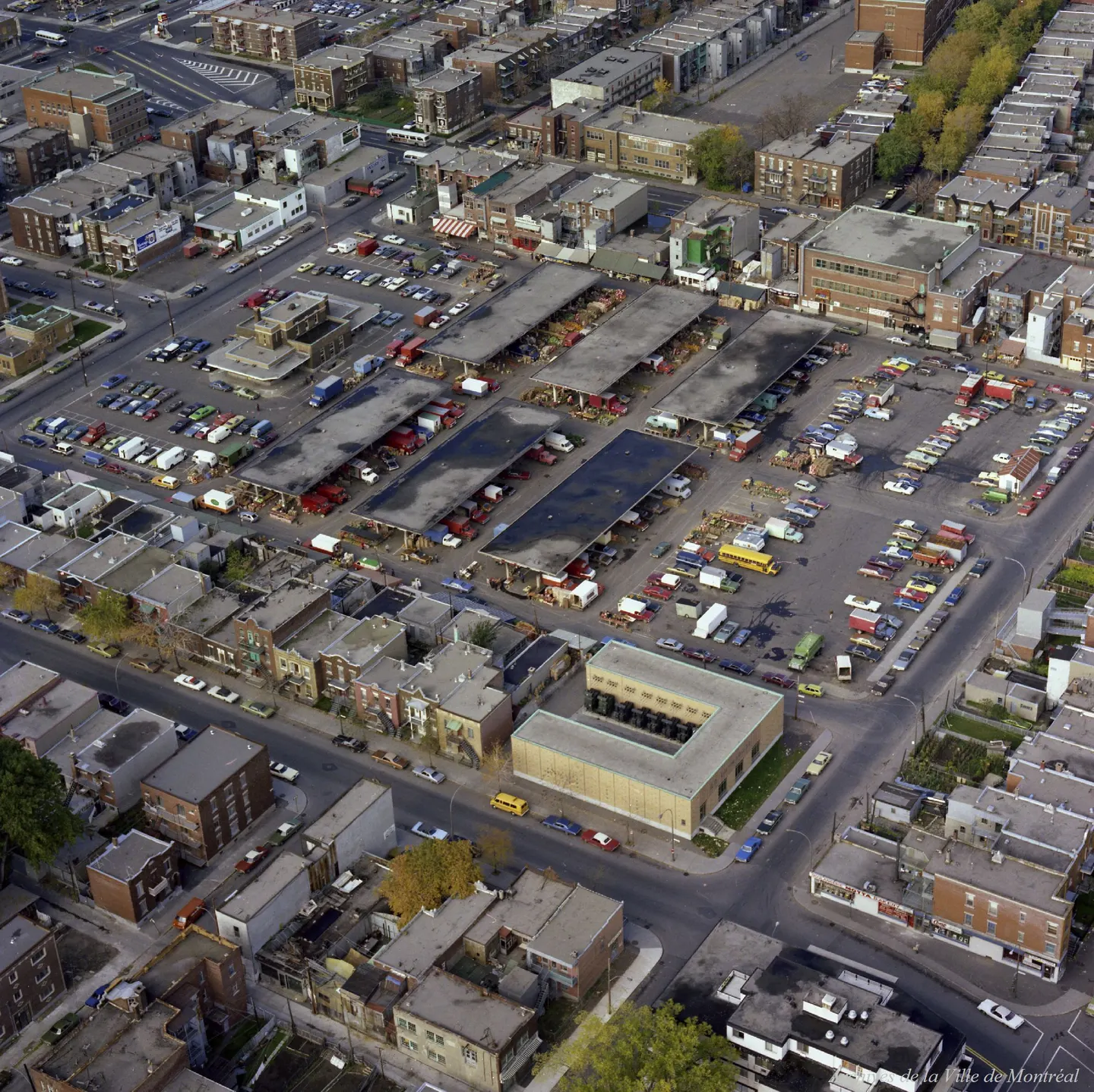 Rue de Montréal avec un bâtiment à tour de l'horloge, des voitures et camions garés et des gens
