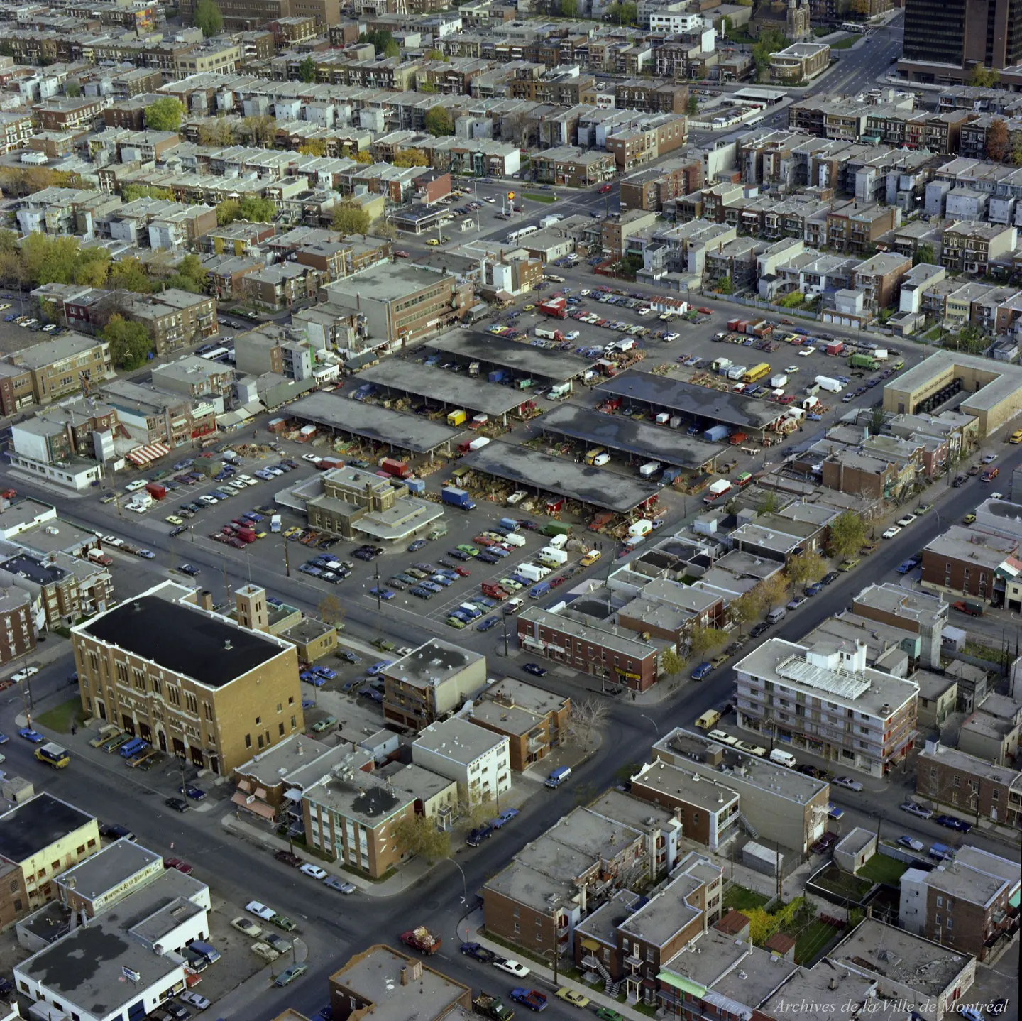 Vue aérienne d'une rue de Montréal avec des voitures et camions garés, bâtiments en arrière-plan
