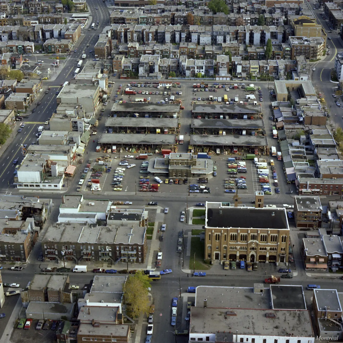 Rue de Montréal avec un bâtiment à tour de l'horloge, des voitures et camions garés, des gens