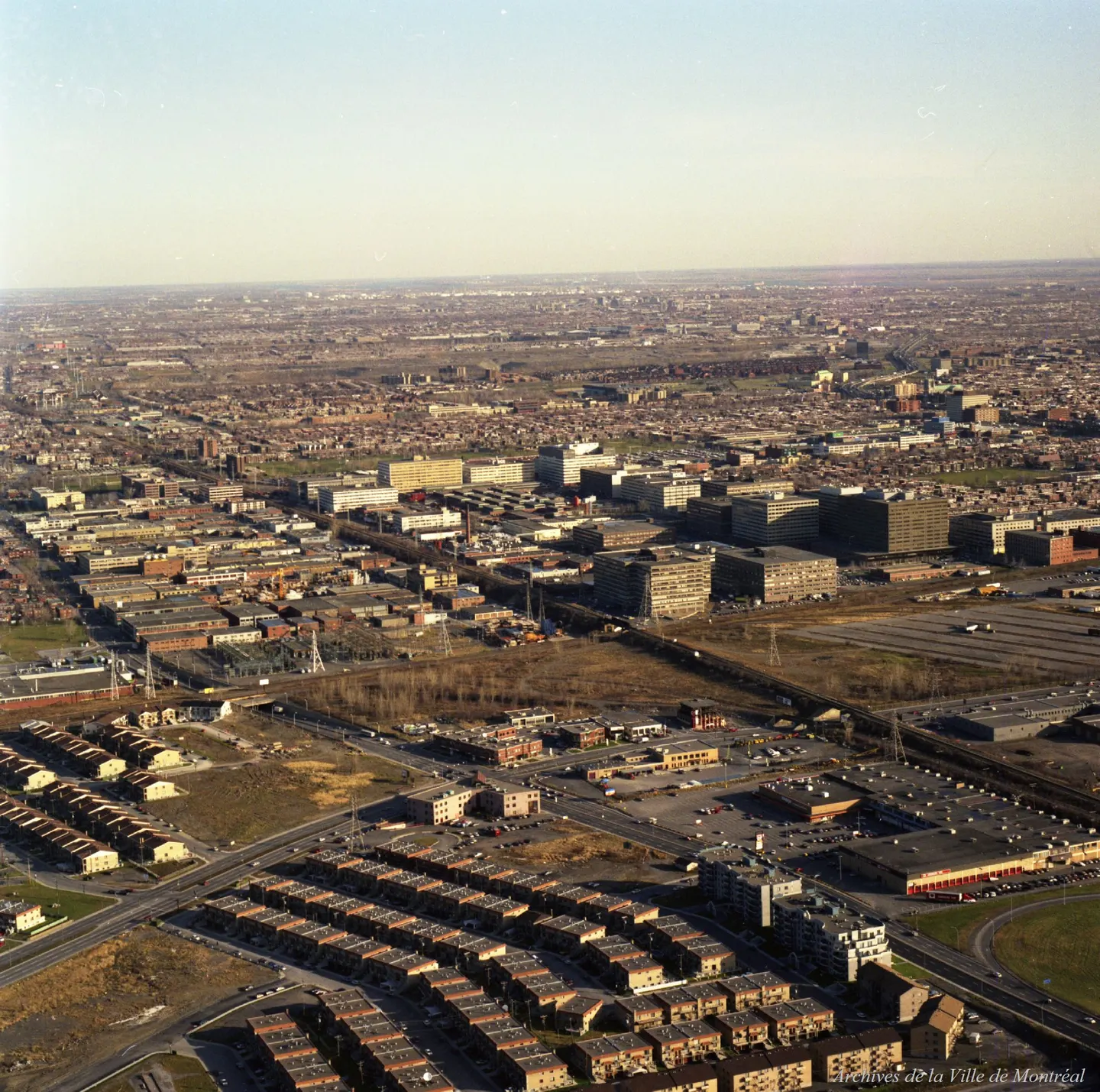 Vue oblique d’une rue de Montréal avec de hauts bâtiments et de nombreuses voitures garées.