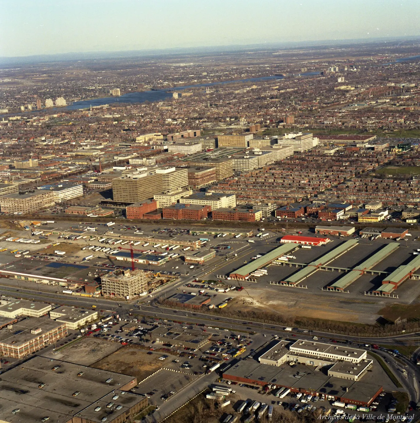 Vue oblique d’une rue de Montréal avec des bâtiments, des voitures et des camions.