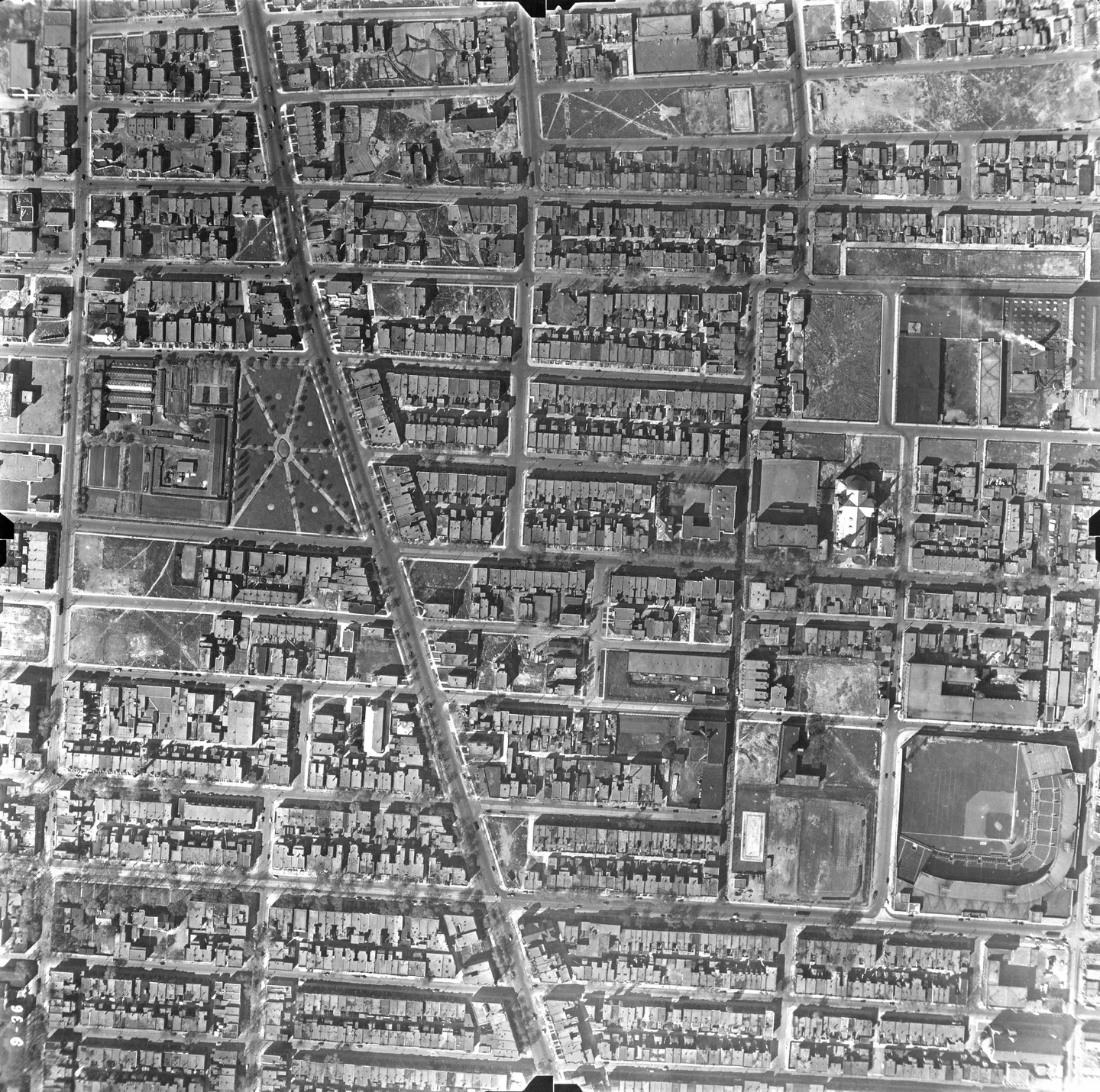 Aerial view of a street with buildings, a baseball field and pedestrians
