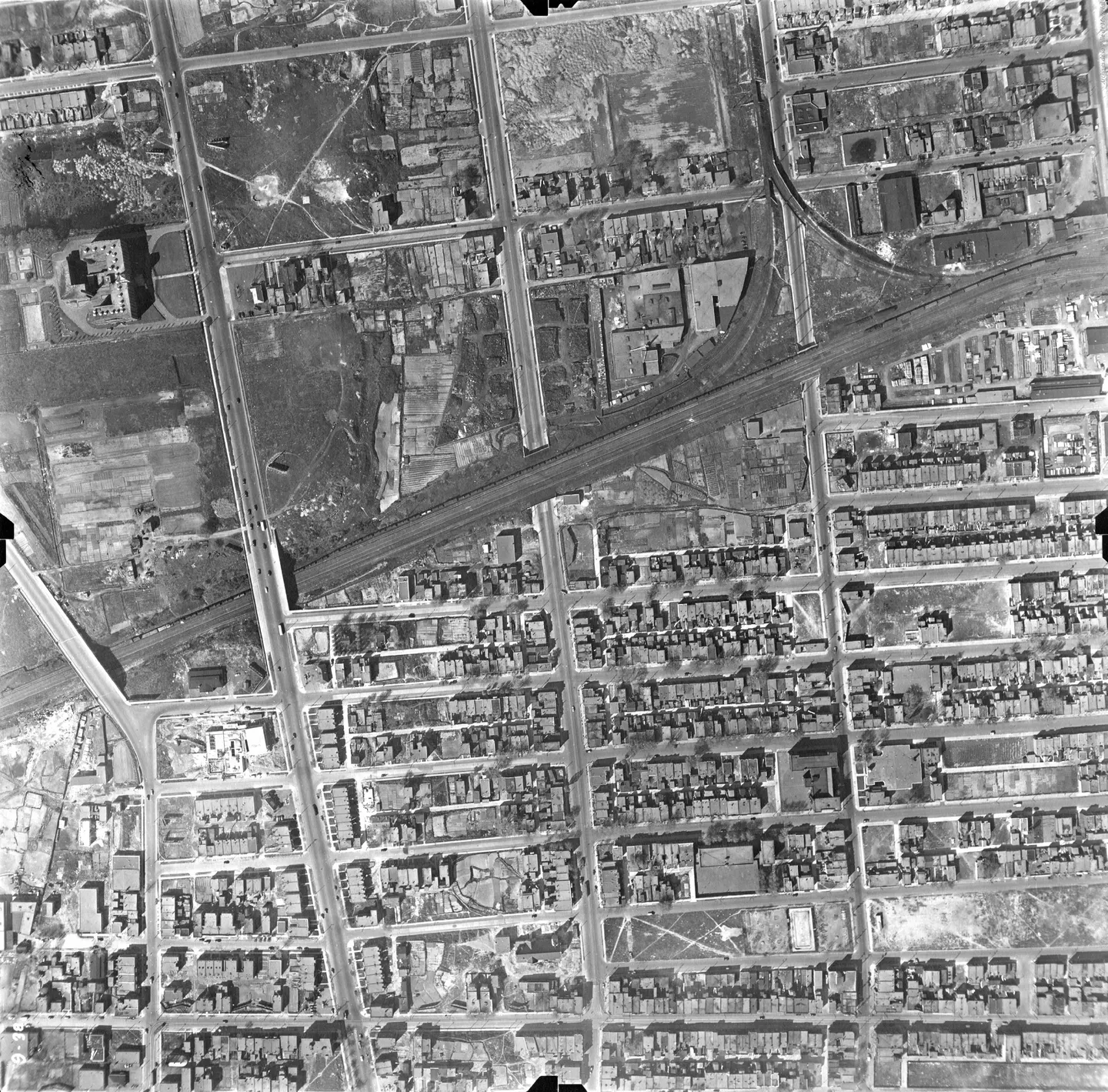 Aerial view of a street lined with buildings and a park, no people or vehicles
