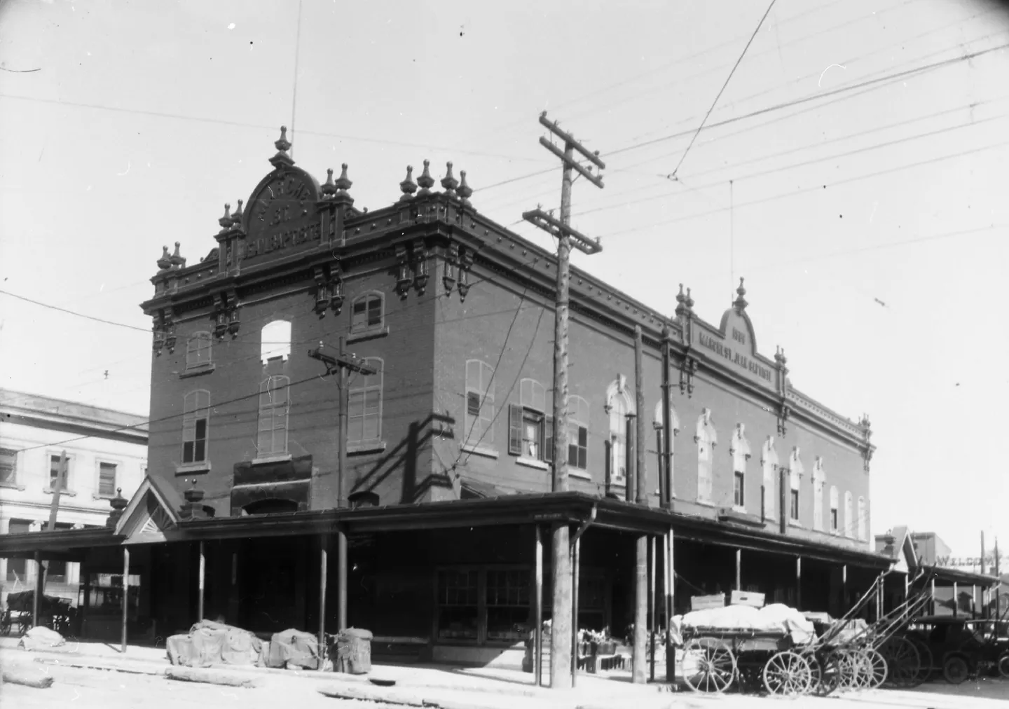 Photographie en noir et blanc d'un bâtiment montréalais du 1930 avec une tour d'horloge, des passants et un char à cheval